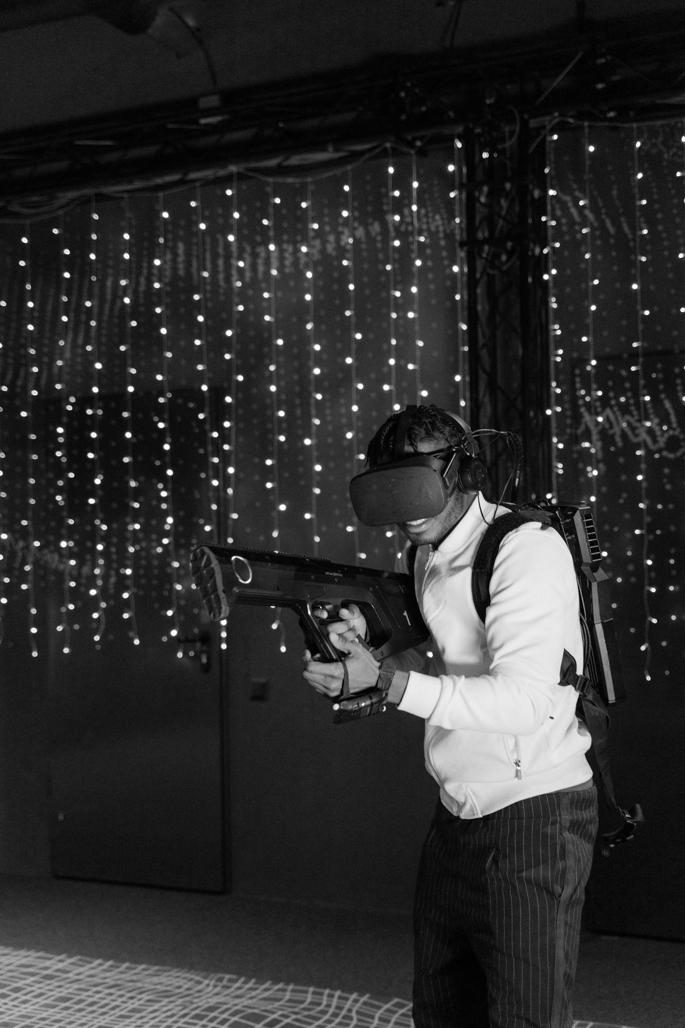 Man engaged in virtual reality simulation, holding a VR gun in a monochrome setting.